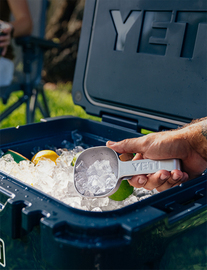 YETI cooler with ice and a scoop, person's hand visible