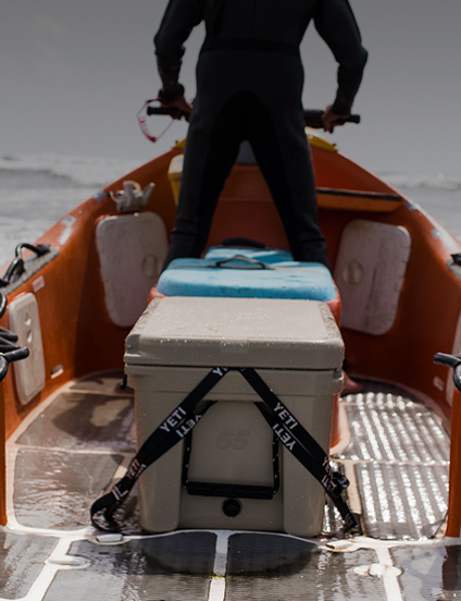 Person on a boat with a YETI cooler on a gray background