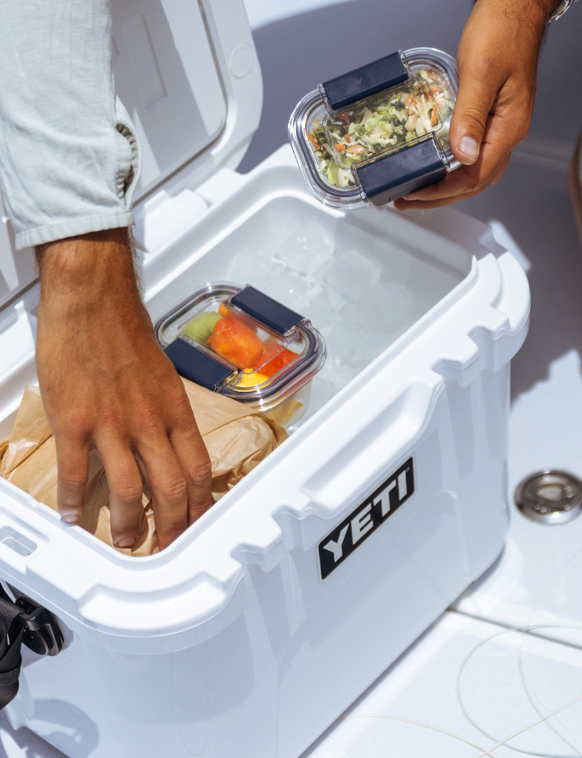 Yeti cooler with hands placing food items inside