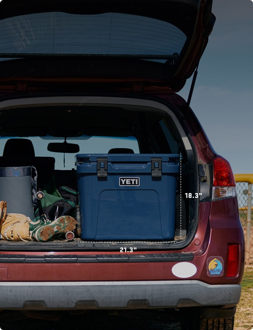 Blue YETI cooler in the trunk of a car with measurements displayed.