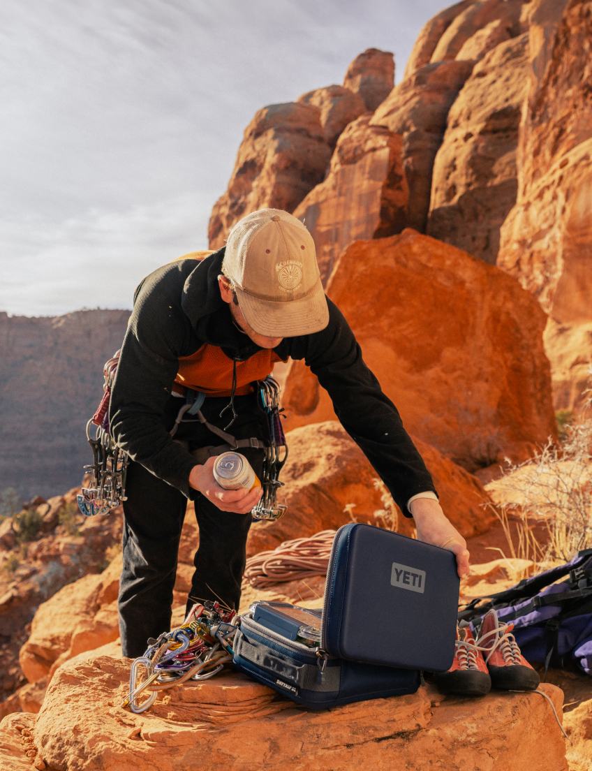 Person with climbing gear and YETI cooler in a rocky outdoor setting