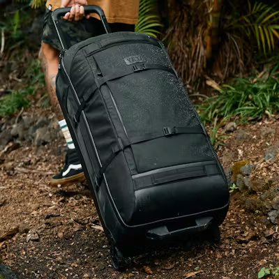 Black rolling duffel bag being carried outdoors on a trail